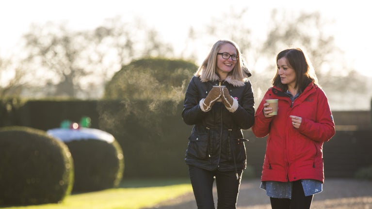 Two visitors enjoying a hot drink while walking in the grounds at Ickworth, Suffolk